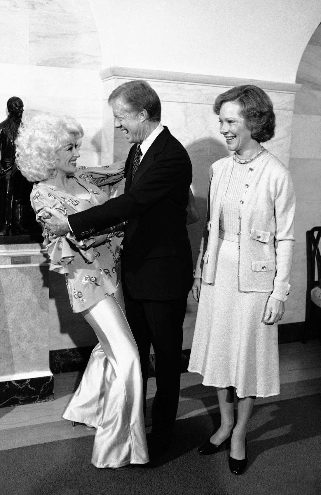 1979 年 10 月 2 日：周二，吉米·卡特总统和多莉·帕顿在华盛顿白宫接见时拥抱。卡特总统在行政官邸为一群乡村音乐艺人举办了午宴。