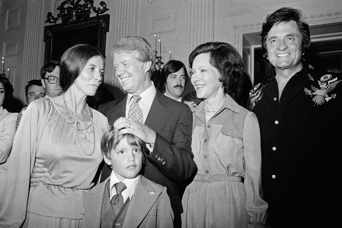 1977 年 6 月 14 日：卡特总统和夫人在华盛顿特区白宫访问期间，与歌手约翰尼·卡什 (Johnny Cash) 和他的妻子琼·卡特 (June Carter) 聊天。与他们在一起的是歌手的儿子约翰·卡特·卡什 (John Carter Cash)。早些时候，卡什在国会大厦的卖旗日仪式上唱歌。