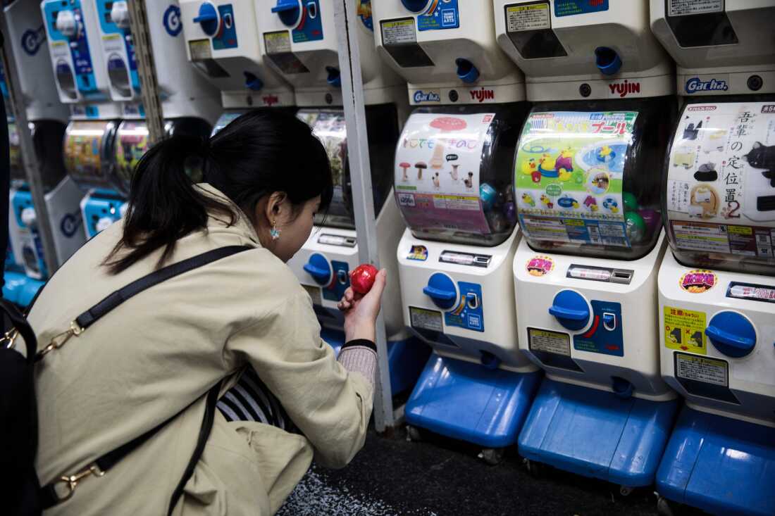 在2017年11月14日拍摄的这张照片中，一名妇女在东京Akihabara地区的一家商店寻找胶囊玩具时看着她新近的物品。
