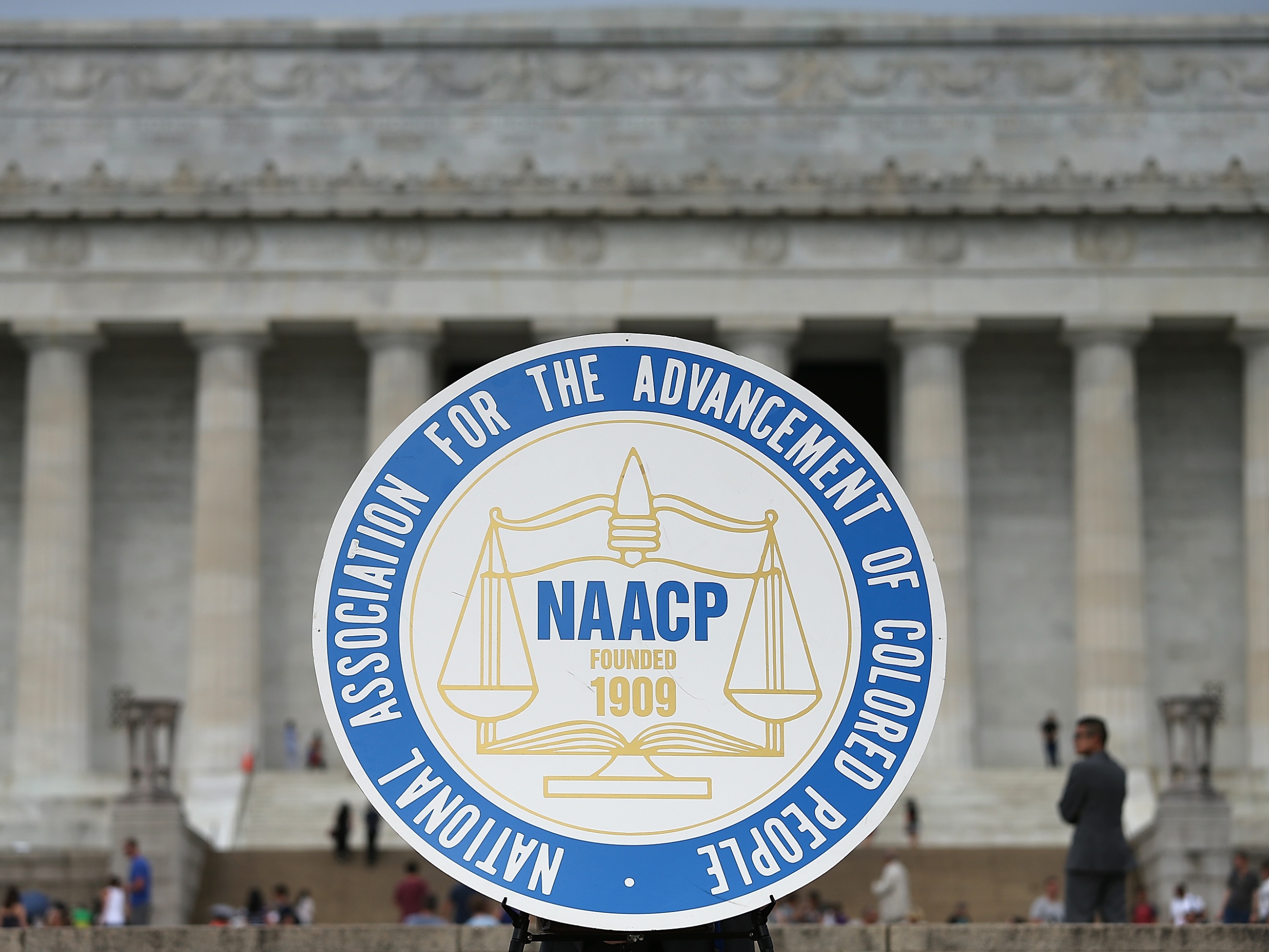 NAACP徽标以司法规模和1909年的成立日期为特色，在2015年华盛顿特区举行的活动中显示