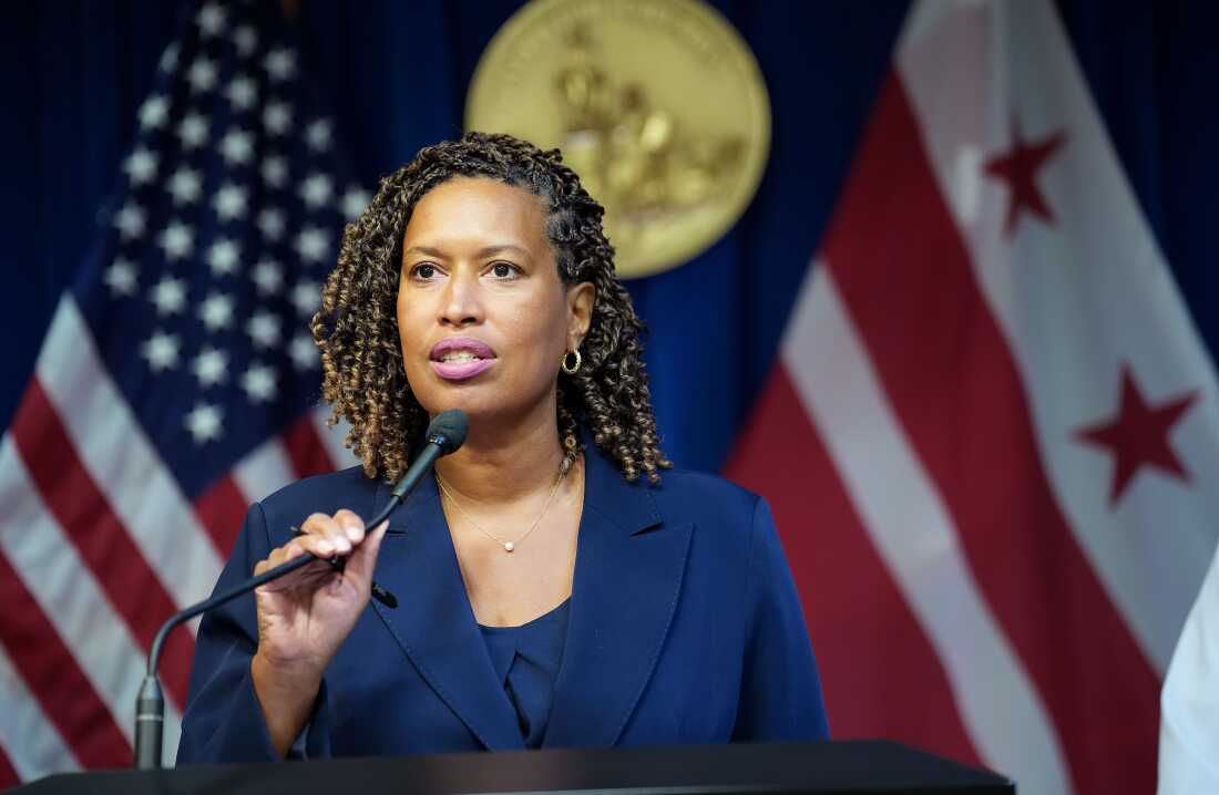 华盛顿特区，市长穆里尔·鲍瑟（Muriel Bowser）站在讲台上时说话成麦克风。她后面是美国国旗和DC国旗。