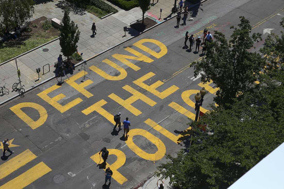 人们在2020年6月8日在华盛顿特区的白宫附近的街道上绘制了“罚款警察”之后，沿着第16街行走，而许多民主党人试图与政策保持距离，特朗普和共和党总统用它将其描绘成犯罪薄弱。
