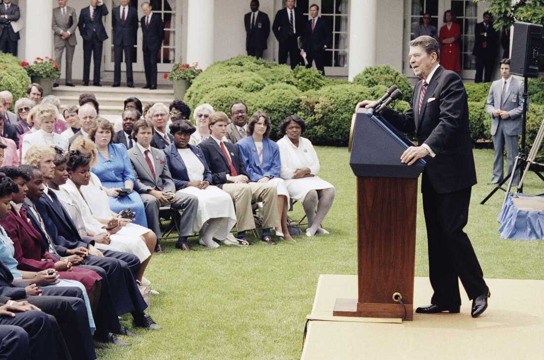总统罗纳德·里根（Ronald Reagan）于1986年5月13日在华盛顿特区的白宫玫瑰园（Washington）向北卡罗来纳州埃登顿市的约翰·A·霍尔姆斯高中高中班发表演讲。