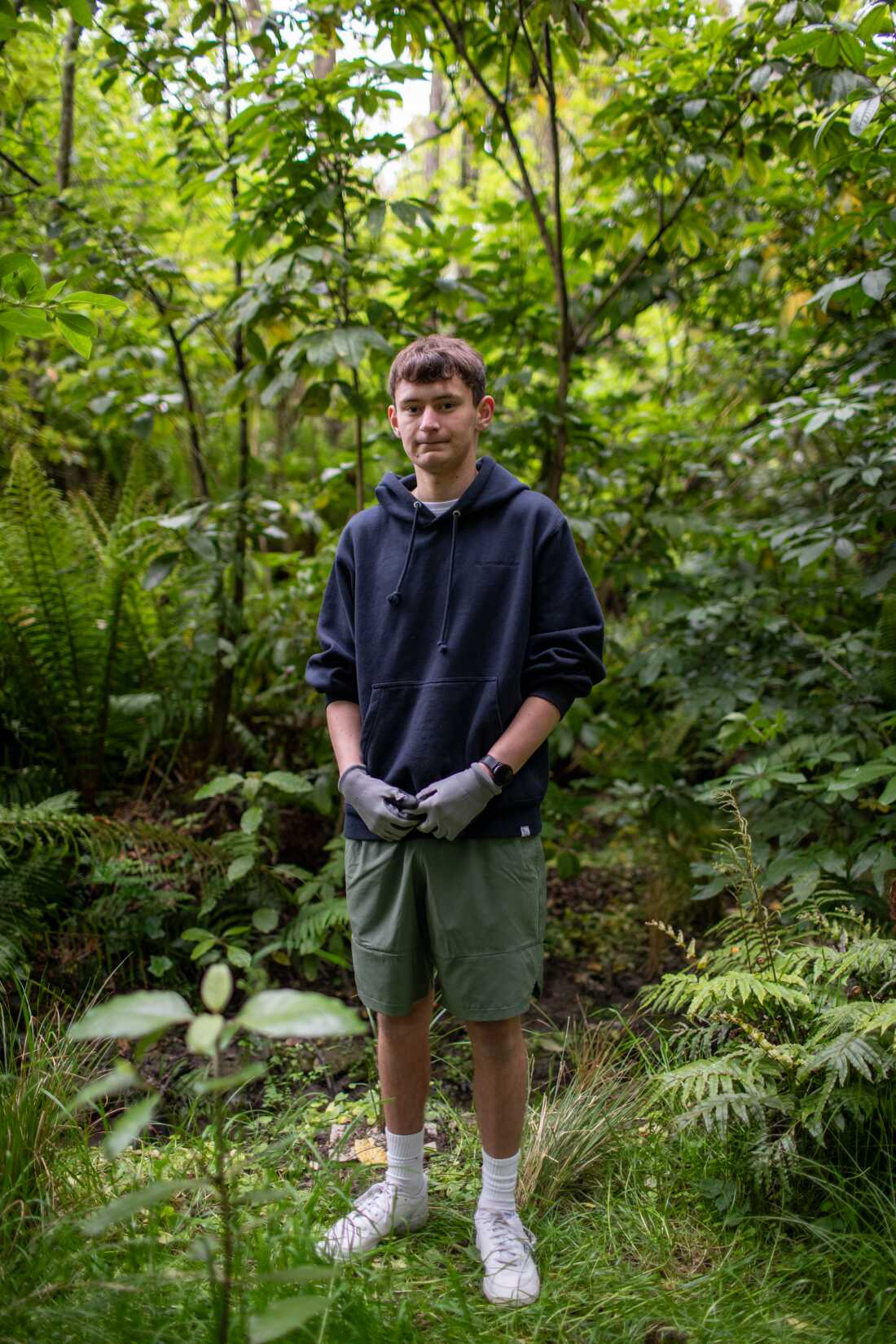 城镇腰带凯蒂亚基（Kaitiaki）的少年芬恩·希伯特（Finn Hibbert）站在一个小森林公园的一条小溪附近的一条封口中。希伯特说，保护正在成为他这一代的一部分。 “我们开始看到的鸟越多，我们就会看到植树，工作和陷阱的结果。”