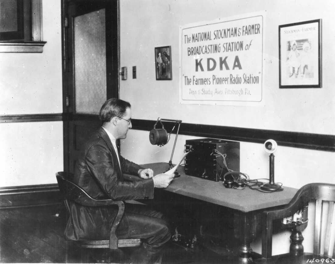1922 年，匹兹堡 KDKA 广播员 Frank Mullen 对着麦克风朗读广播内容。