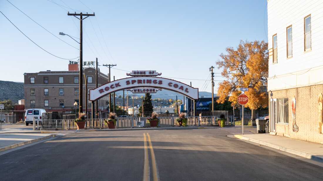 图中显示一条街道通向一个拱形标志，上面写着“罗克斯普林斯煤炭之家”和“欢迎光临”。道路或人行道上没有人或汽车。  