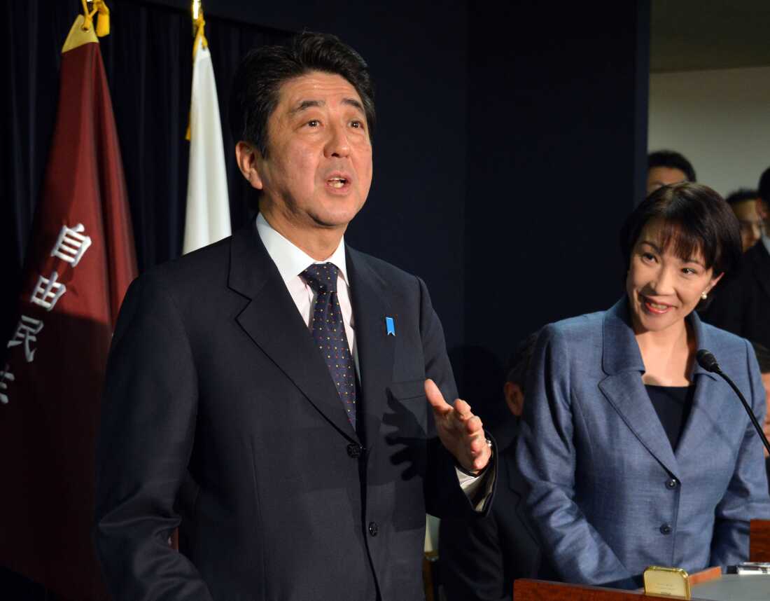 2012 年 12 月，高市看着即将上任的首相安倍晋三在东京向媒体发表讲话。 