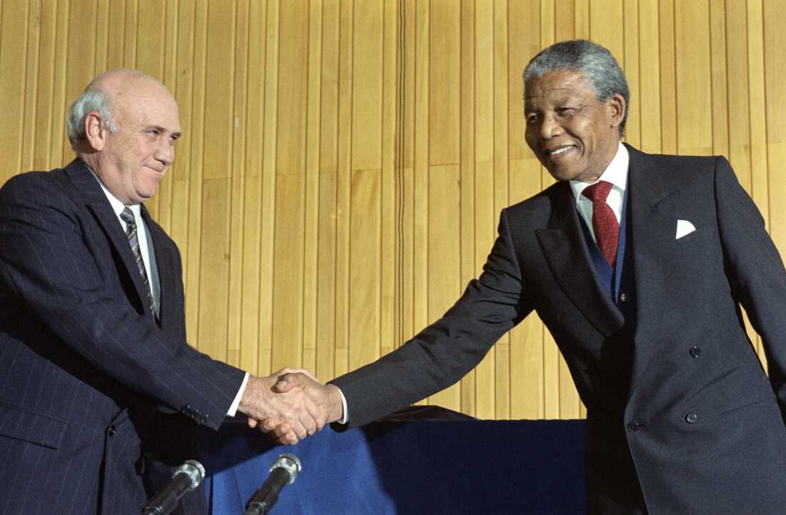 在 1990 年的联合新闻发布会上，南非前总统德克勒克 (FW de Klerk) 与反种族隔离领导人纳尔逊·曼德拉 (Nelson Mandela) 握手，后者将成为种族隔离后第一位民选南非总统。