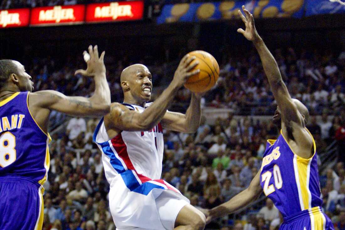 2004 年 6 月 10 日，在密歇根州奥本山宫殿举行的 NBA 总决赛第 3 场上半场，底特律活塞队昌西·比卢普斯 (1) 在洛杉矶湖人队科比·布莱恩特 (8) 和加里·佩顿 (20) 之间投篮。
