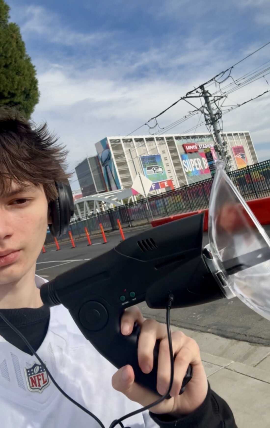 这张照片显示 21 岁的 Caden Booth 站在加利福尼亚州圣克拉拉的李维斯体育场外。他拿着一个看起来像扩音器的录音设备，通常用于捕捉鸟的声音。